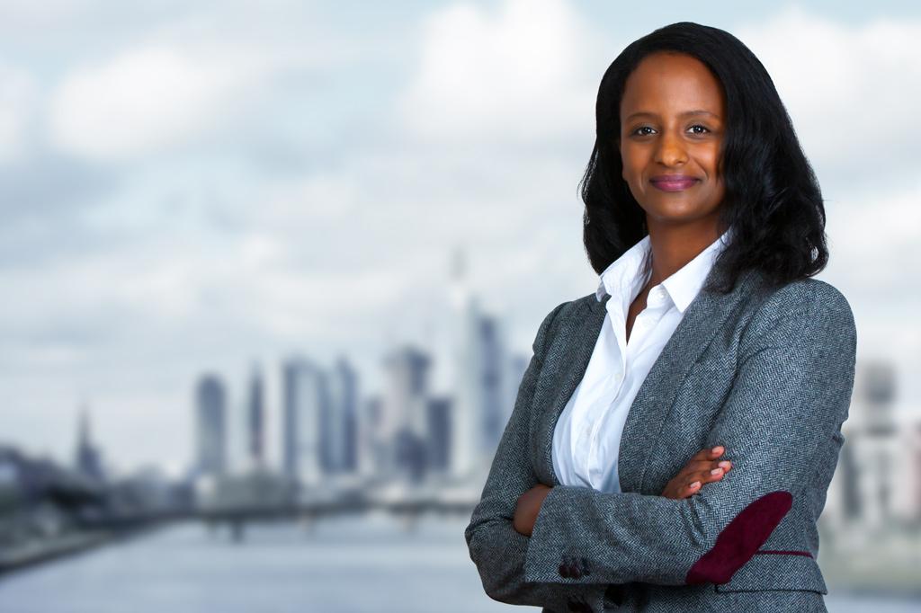 Porträt einer schönen, selbstbewussten, lächelnden afroamerikanischen Geschäftsfrau, die mit verschränkten Armen | Businessfotografie dc-photodesign