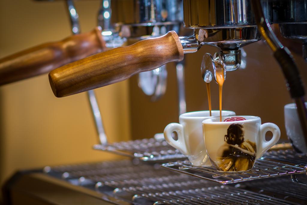 Brandingfotografie einer Espressomaschine, die Kaffee in Tassen gießt.